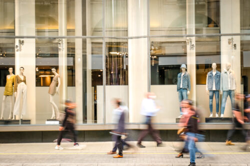 Motion blurred people walking past retail shop window