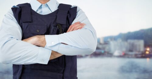 Security guard mid section arms folded against blurry skyline