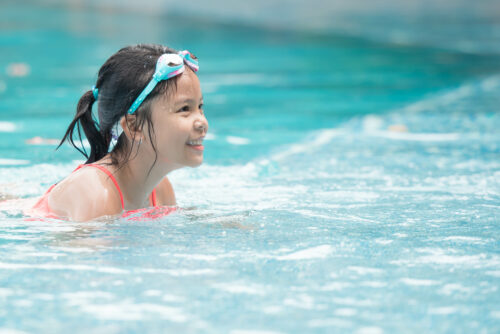 smiling child wearing swimming glasses in swimming pool. little